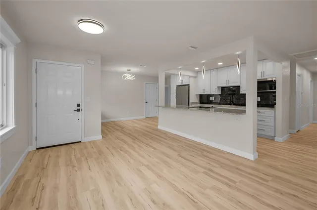 a view of a kitchen with cabinets stainless steel appliances wooden floor and a window