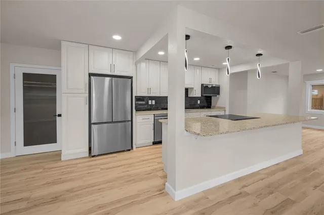 a kitchen with stainless steel appliances granite countertop a refrigerator and a stove top oven