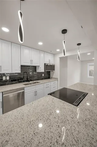 a kitchen with granite countertop a stove and white cabinets