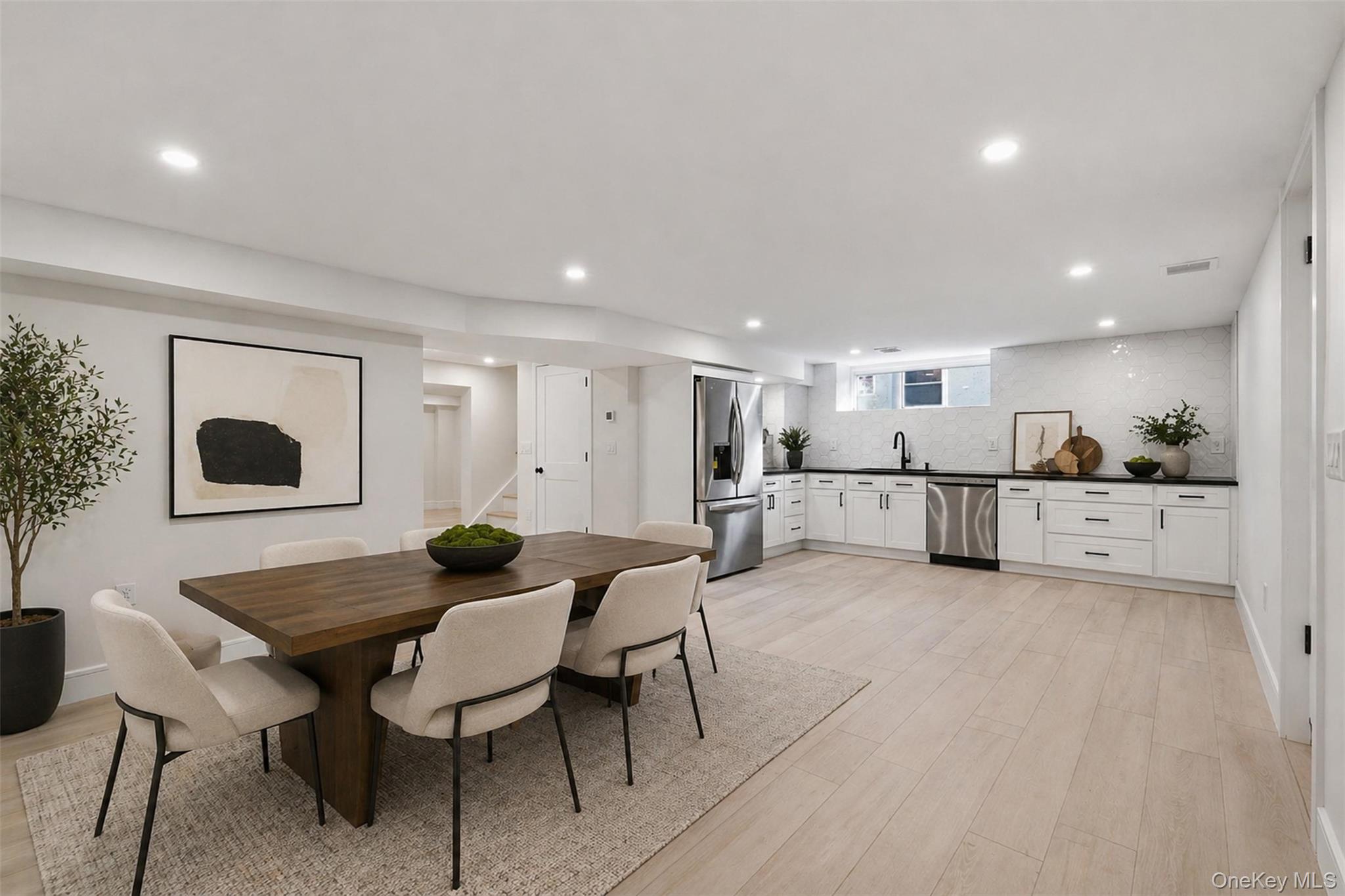 40 Calhoun Avenue New Rochelle, NY 10801 - Photo 34 of 49 Open-concept living area featuring light wood-finish flooring, recessed lighting, and a contemporary kitchen with stainless steel appliances, white cabinetry, and dark countertops