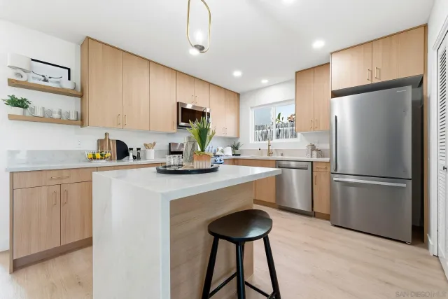 a kitchen with a refrigerator a sink cabinets and wooden floor