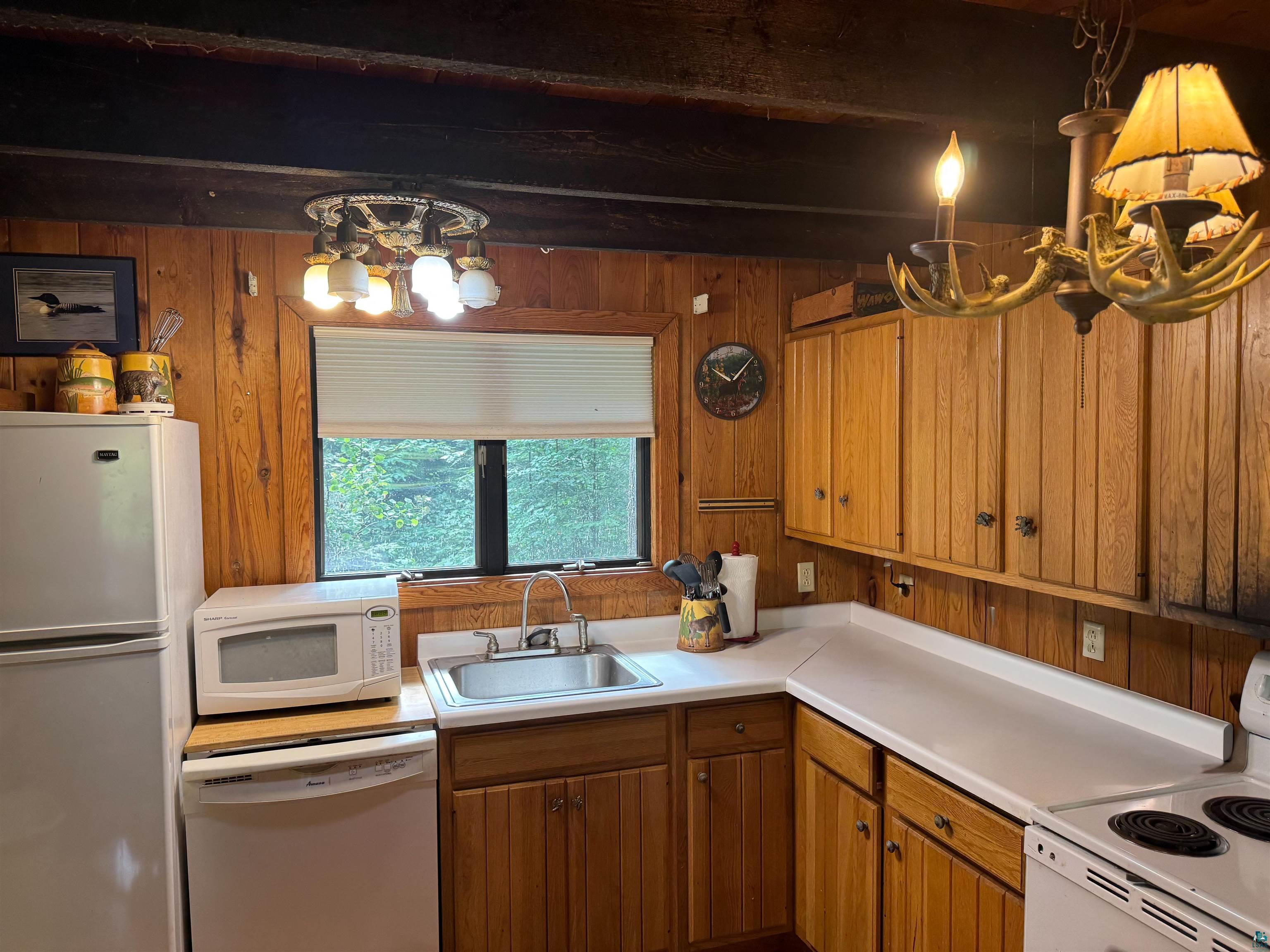 465 South Gunflint Lake Road Grand Marais, MN 55604 - Photo 23 of 46 Kitchen featuring wood paneling, wood cabinetry, stainless steel sink, light-toned countertops, and a window with exterior views