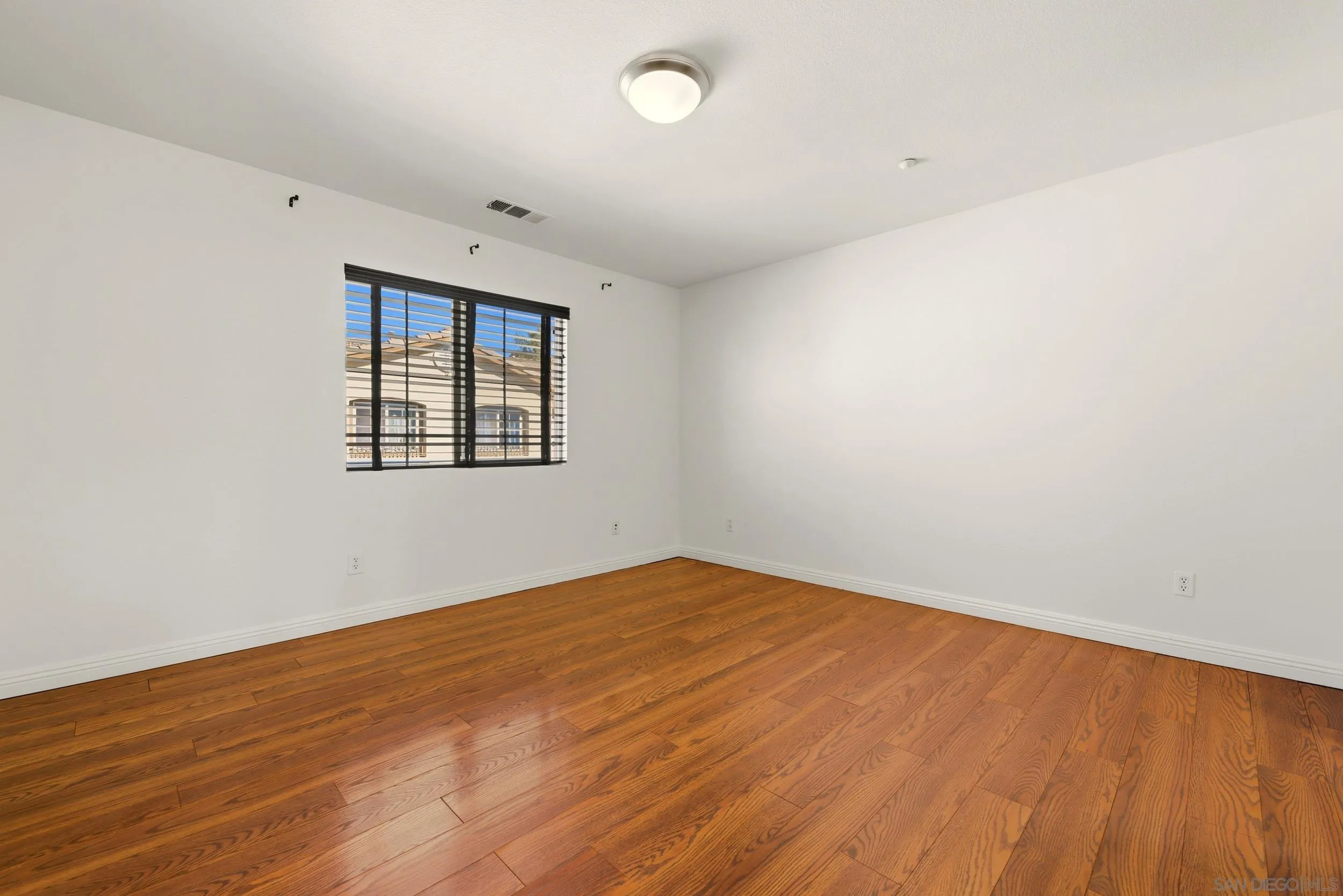 16953 New Rochelle Way, Unit 62 San Diego, CA 92127 - Photo 8 of 21 an empty room with wooden floor and windows
