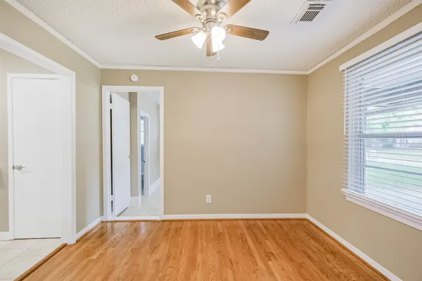 a view of an empty room with window and wooden floor