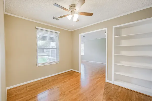 a view of an empty room with a window and wooden floor