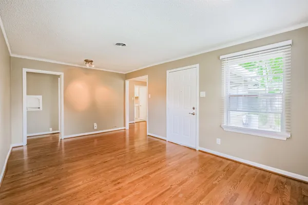 a view of an empty room with wooden floor and a window