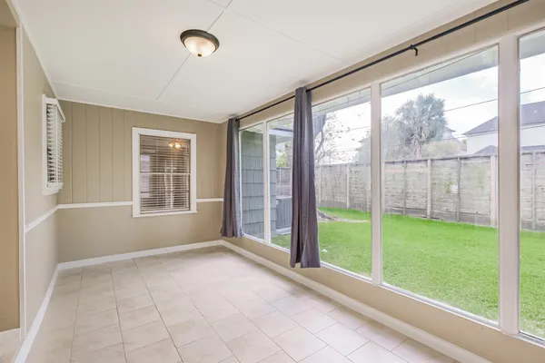 a view of an empty room with windows and view of kitchen