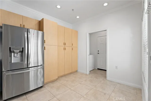 a view of a refrigerator in kitchen and an empty room with wooden floor