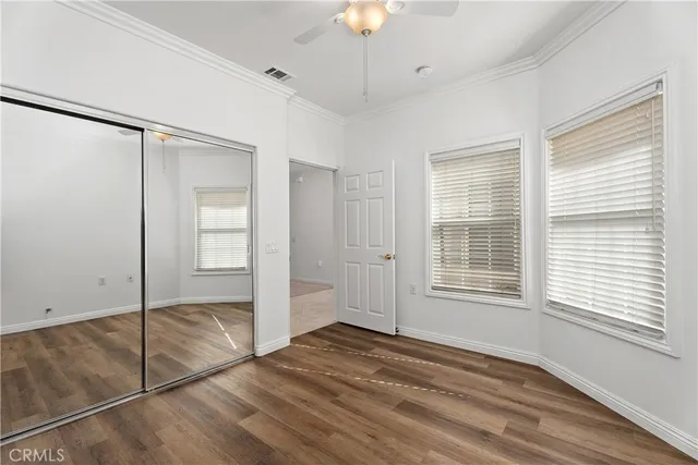 a view of empty room with wooden floor and fan