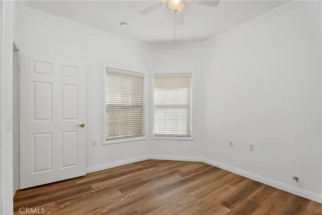 an empty room with wooden floor cabinet and windows