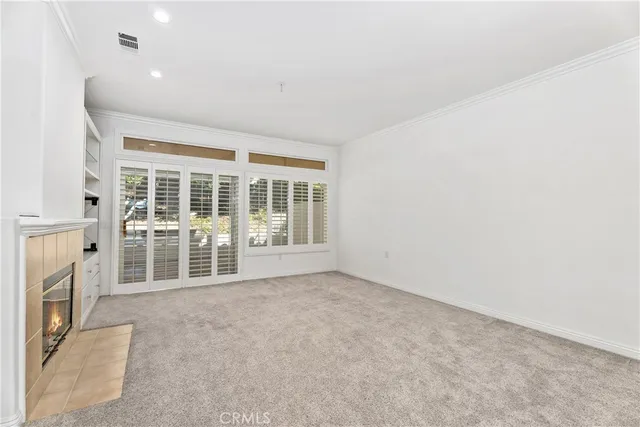 an empty room with a fireplace and large windows