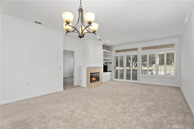 a view of a livingroom with a fireplace a chandelier and windows