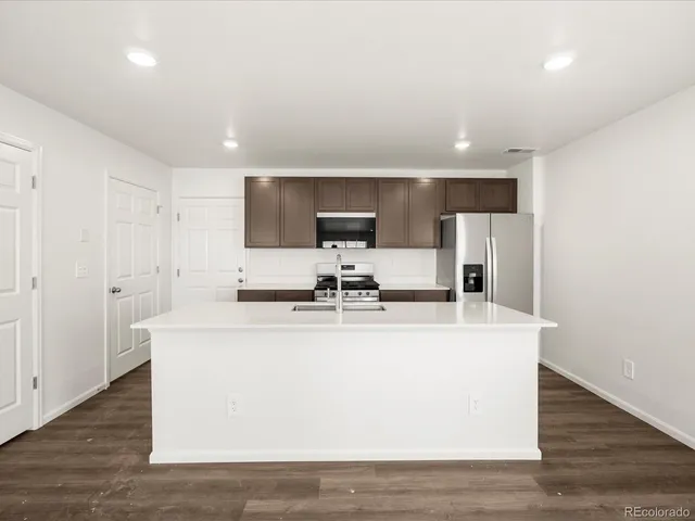 a view of kitchen with stainless steel appliances wooden floor and window
