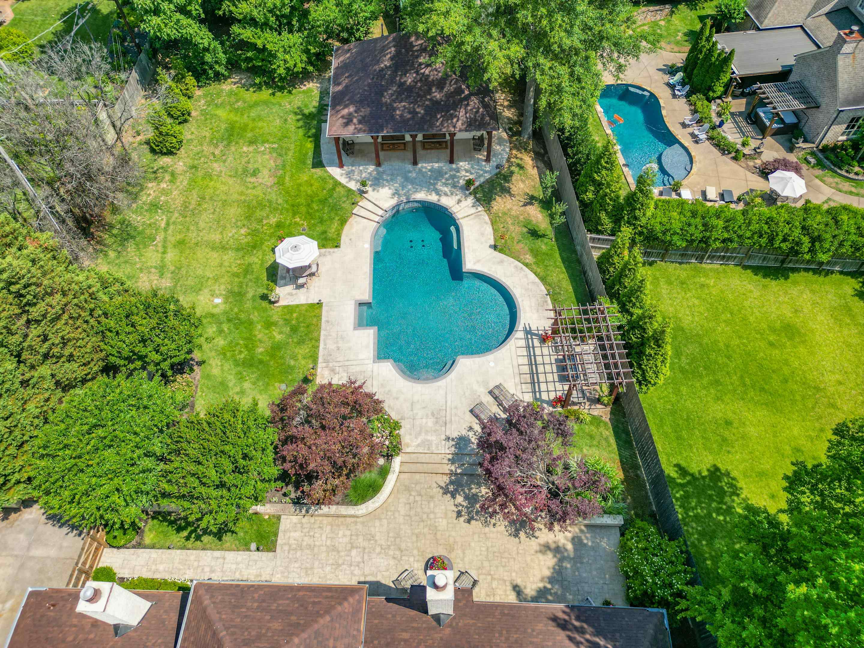 5074 Shady Grove Road Memphis, TN 38117 - Photo 24 of 25 The beautifully landscaped backyard completes the picture, creating a serene backdrop for outdoor enjoyment. Whether you seek a quiet afternoon by the pool, a festive gathering with loved ones, or simply a place to unwind, this is the perfect spot.