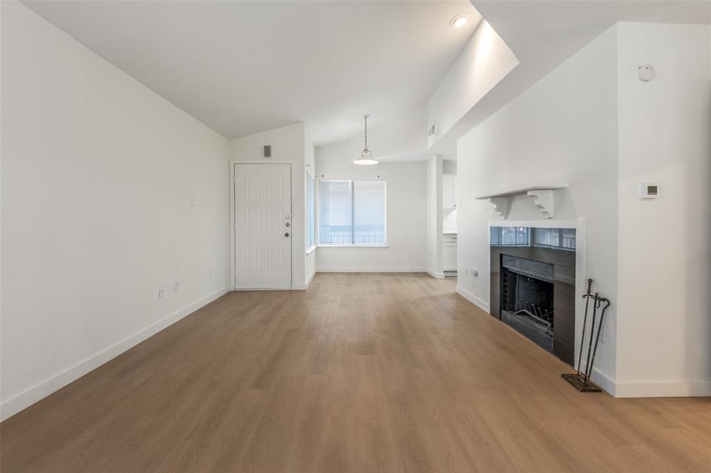 5550 Spring Valley Road, Unit D31 Dallas, TX 75254 - Photo 4 of 19 an empty room with wooden floor and fireplace