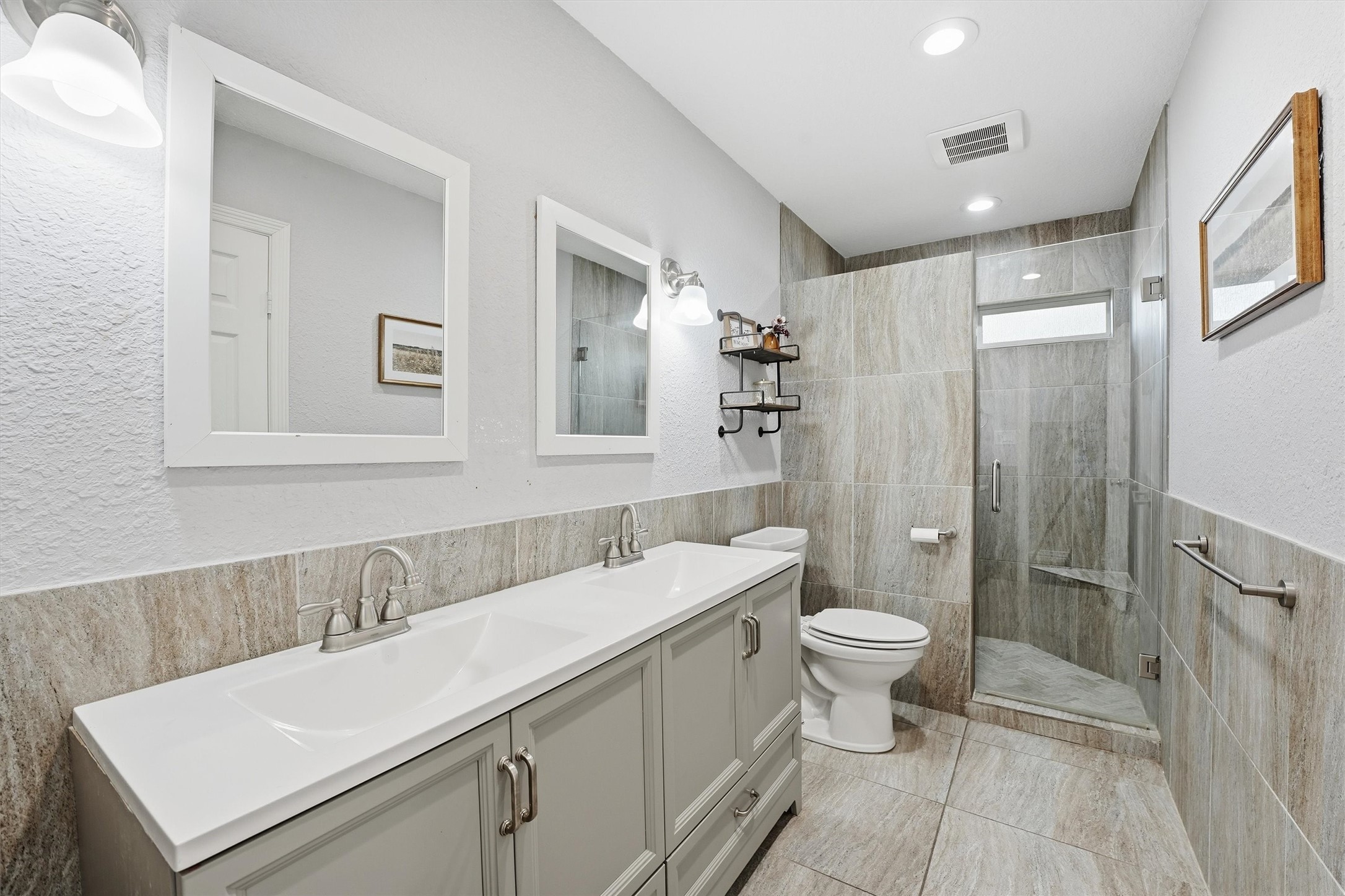 611 Reidland Road Crosby, TX 77532 - Photo 16 of 35 This bathroom features a modern design with a spacious walk-in shower, dual sinks with sleek fixtures, and ample lighting. Neutral tones and stylish tilework create an elegant and inviting atmosphere.