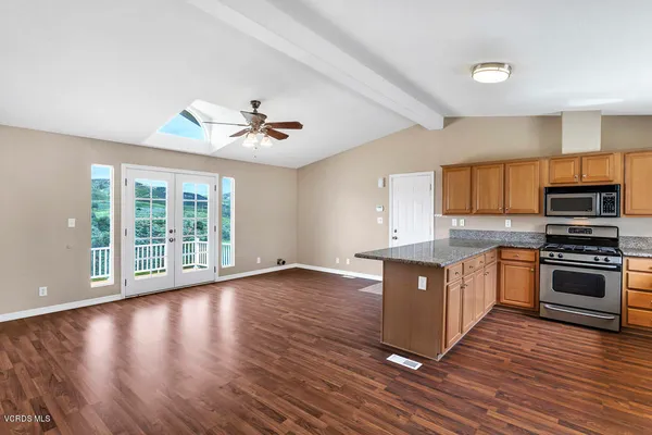 a large kitchen with wooden floors and stainless steel appliances