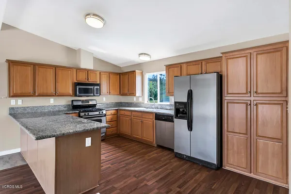 a kitchen with granite countertop stainless steel appliances a refrigerator sink microwave and cabinets