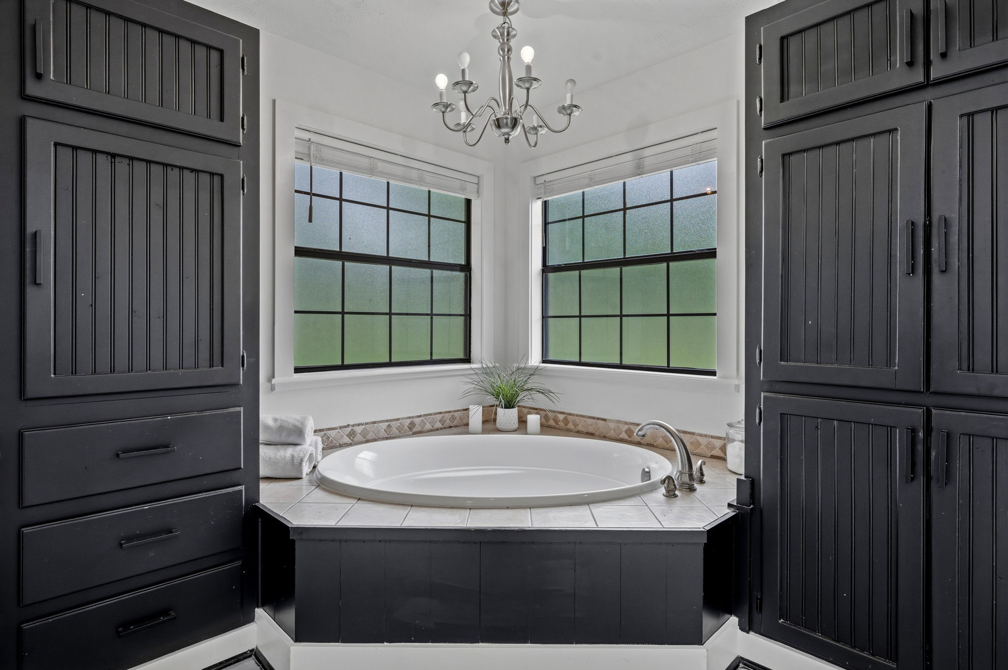 18 East Old Field Road Huffman, TX 77336 - Photo 19 of 35 Indulge in relaxation within the luxurious soaking tub perfectly positioned beneath oversized corner windows and framed by dramatic custom cabinetry that adds depth, warmth, & architectural sophistication.