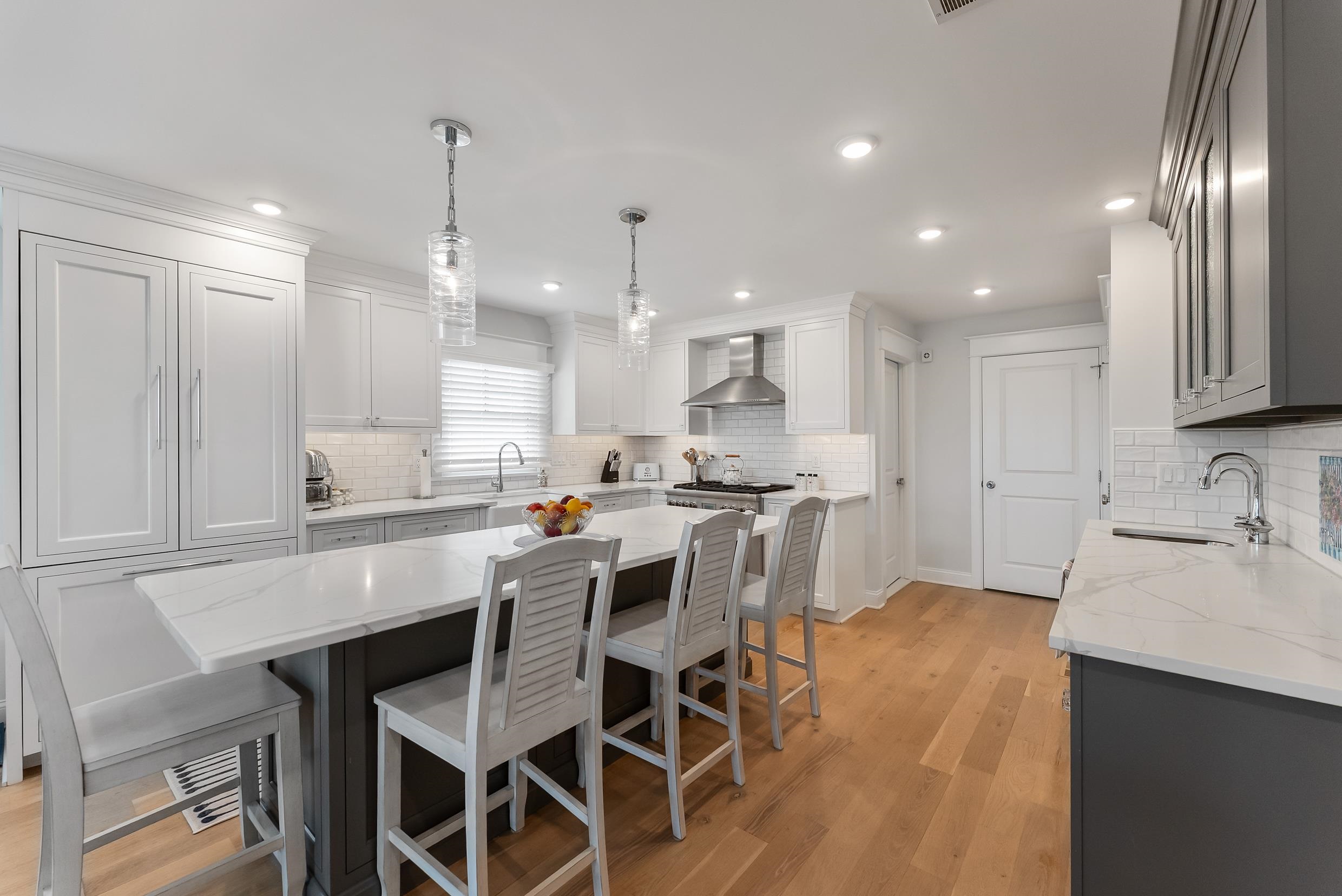 253 35th, Unit WEST Avalon, NJ 08202 - Photo 23 of 43 a kitchen with a dining table chairs wooden cabinets and wooden floor
