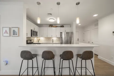 a kitchen with stainless steel appliances a table and chairs in it