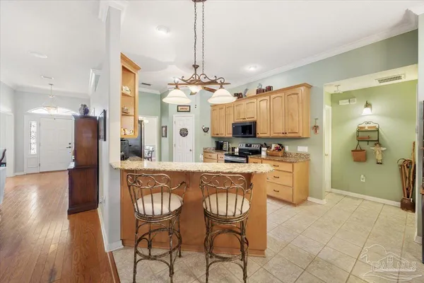 a kitchen with stainless steel appliances kitchen island granite countertop a refrigerator a stove a sink dishwasher and a dining table with wooden floor