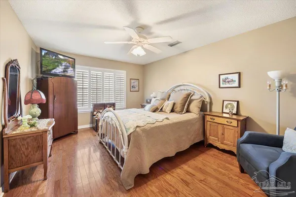 a bedroom with a bed and dresser with wooden floor