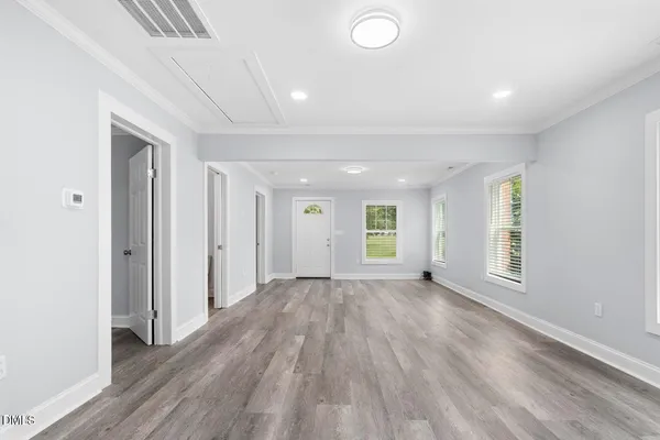 an empty room with wooden floor and windows