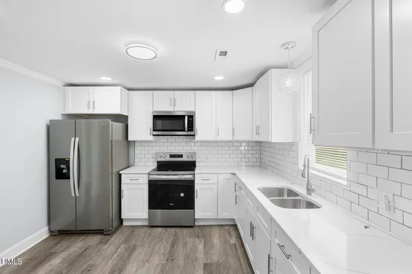 a kitchen with a sink stainless steel appliances and white cabinets