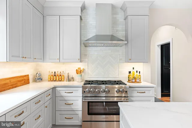 a kitchen with stainless steel appliances a refrigerator a stove and white cabinets