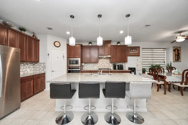 a large kitchen with cabinets chairs and refrigerator