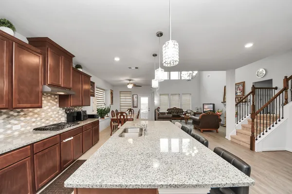 a kitchen with a stove a kitchen island a dining table and chairs with wooden floor