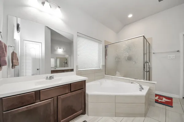a bathroom with a tub a sink and mirror
