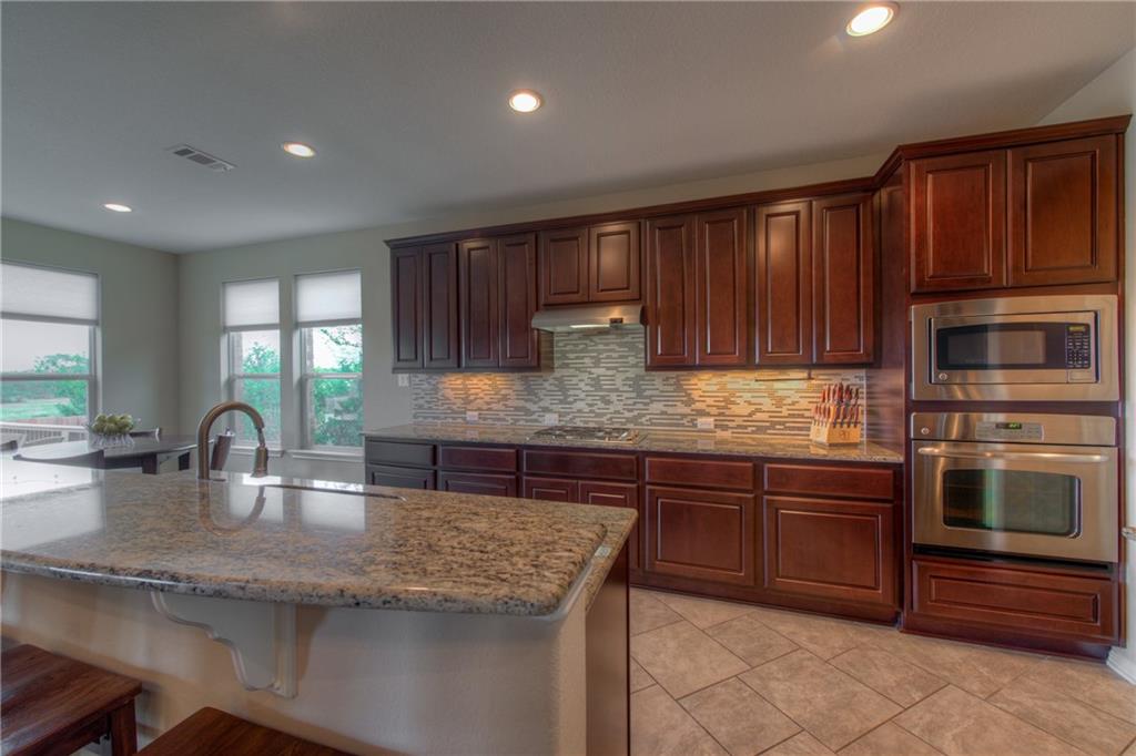 1511 Rimstone Drive Cedar Park, TX 78613 - Photo 12 of 40 a kitchen with kitchen island granite countertop wooden cabinets a sink and dishwasher