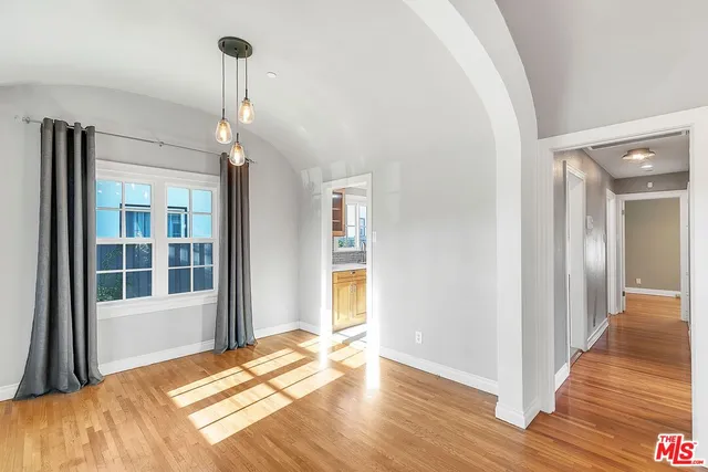 a view of a room with wooden floor front door and windows