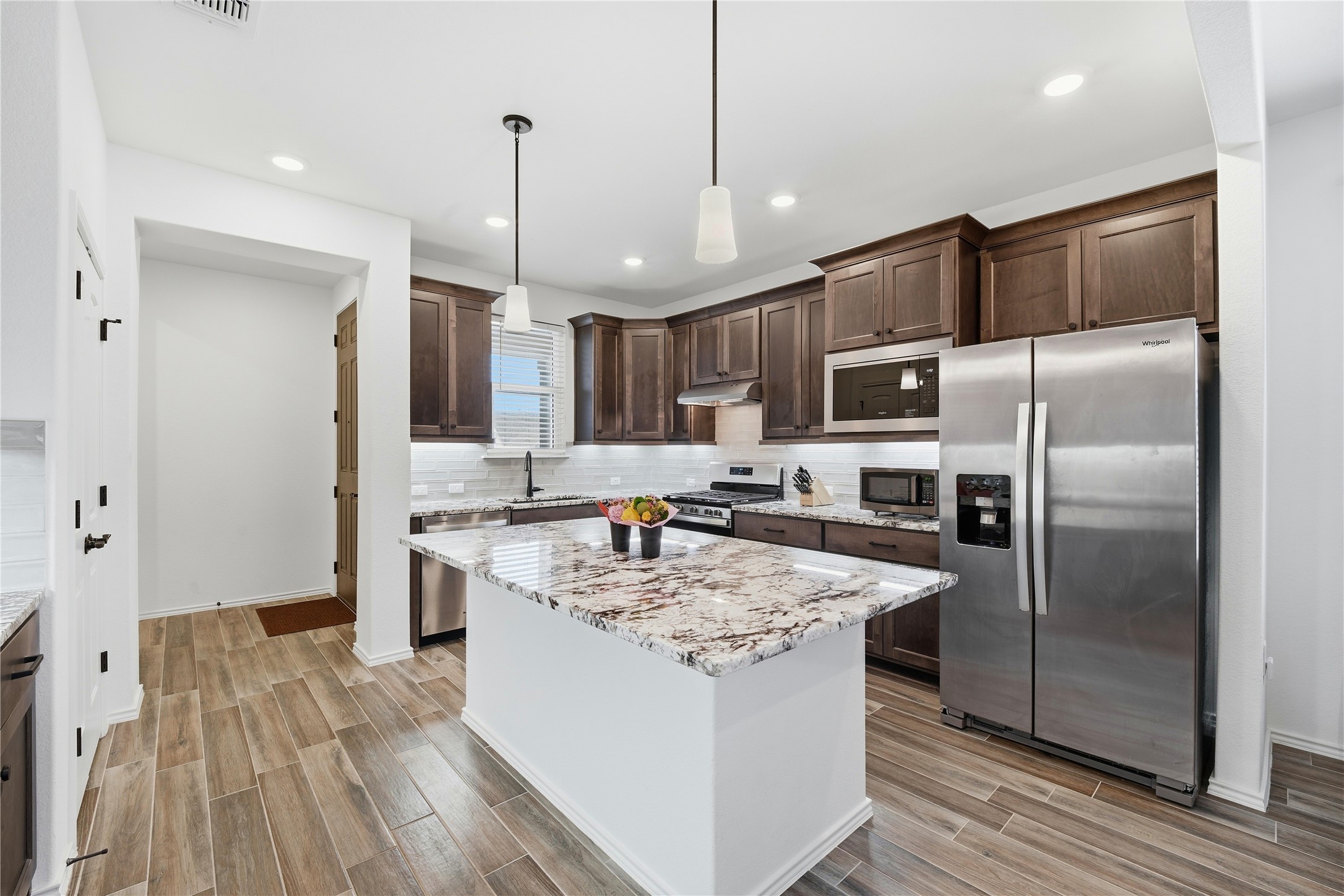 122 Clay Hl Street Georgetown, TX 78633 - Photo 5 of 31 Kitchen featuring stainless steel appliances, dark wood finish cabinetry, decorative light fixtures, and wood finish floors