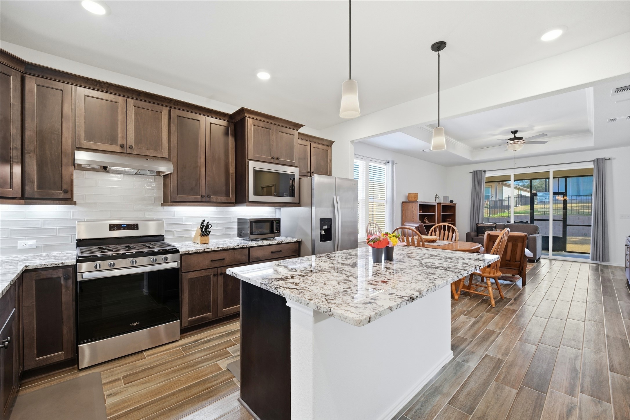 122 Clay Hl Street Georgetown, TX 78633 - Photo 8 of 31 Kitchen with stainless steel appliances, dark wood finish cabinets, pendant lighting, ceiling fan, and light stone countertops