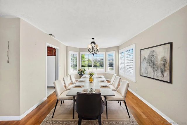 a dining room with wooden floor a chandelier a wooden table and chairs
