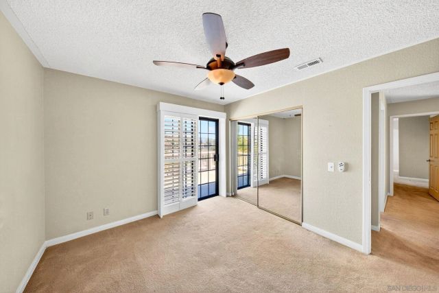 an empty room with windows and ceiling fan