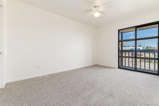 an empty room with a ceiling fan and windows