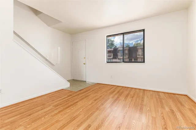 a view of an empty room with wooden floor and a window