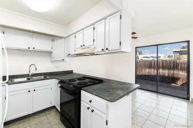 a kitchen with granite countertop a sink stove and cabinets