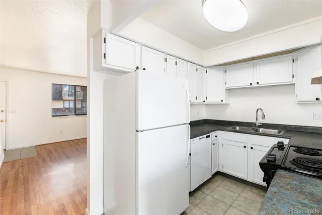 a kitchen with granite countertop a sink a stove a refrigerator and white cabinets