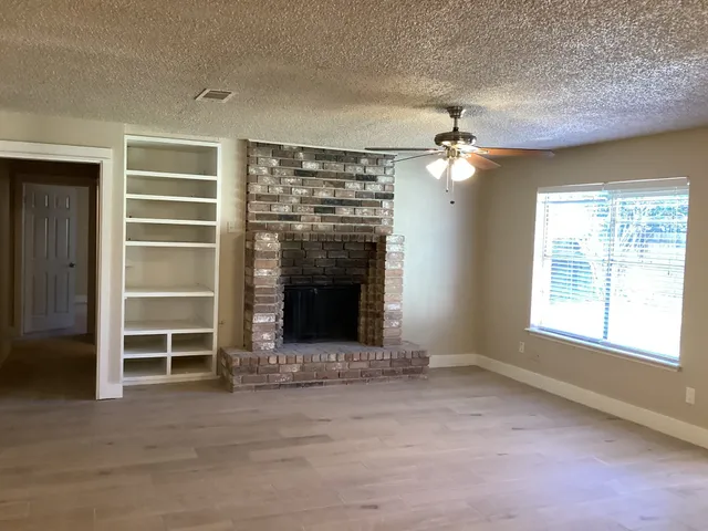 an empty room with a fireplace cabinet and window