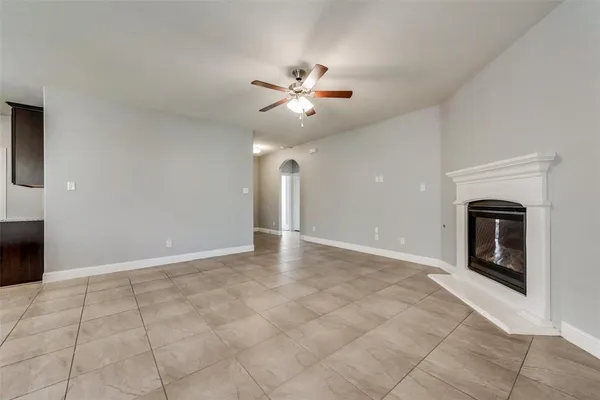 a view of an empty room with a ceiling fan and a fireplace