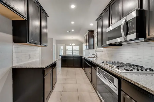 a kitchen with stainless steel appliances granite countertop a stove a sink and a microwave