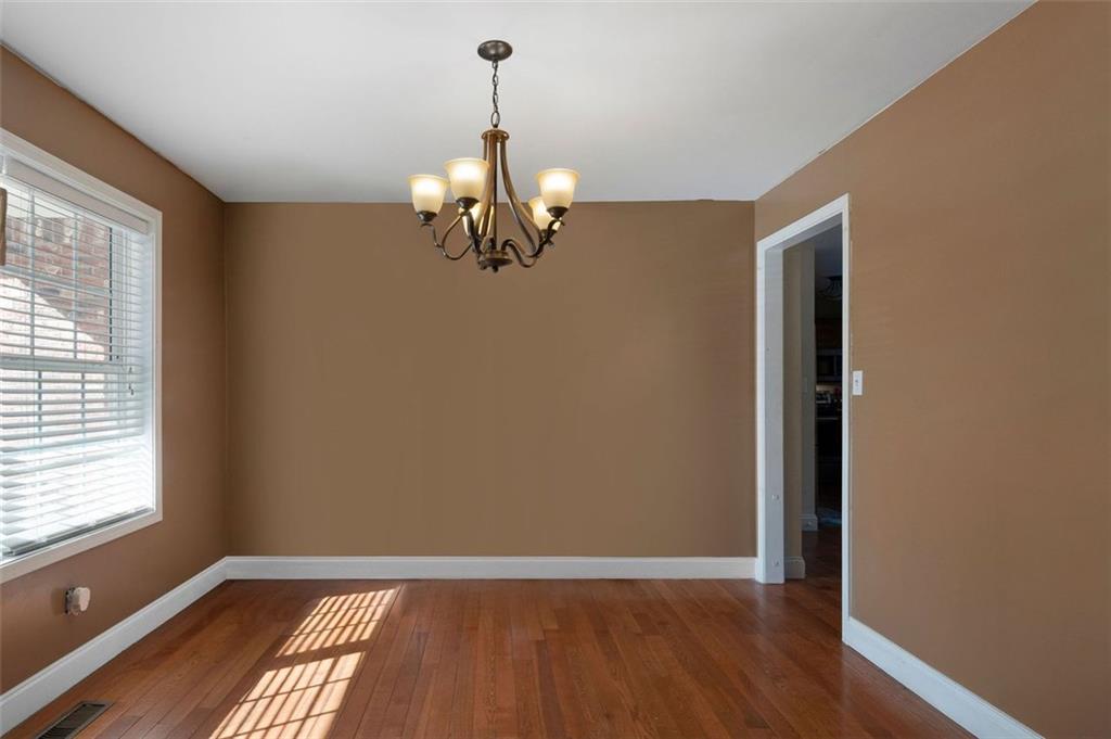 577 Everett Springs Road Southwest Calhoun, GA 30701 - Photo 4 of 34 an empty room with wooden floor chandelier and windows