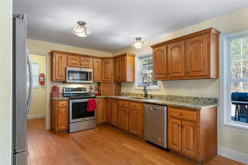 577 Everett Springs Road Southwest Calhoun, GA 30701 - Photo 10 of 34 a kitchen with stainless steel appliances granite countertop a stove top oven a sink and dishwasher a refrigerator with wooden floor