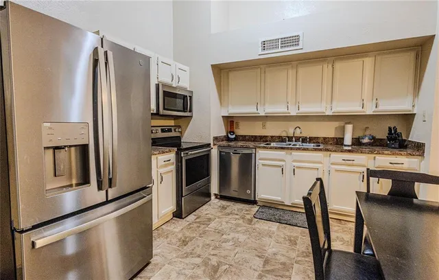 a kitchen with stainless steel appliances granite countertop a stove a sink and a refrigerator