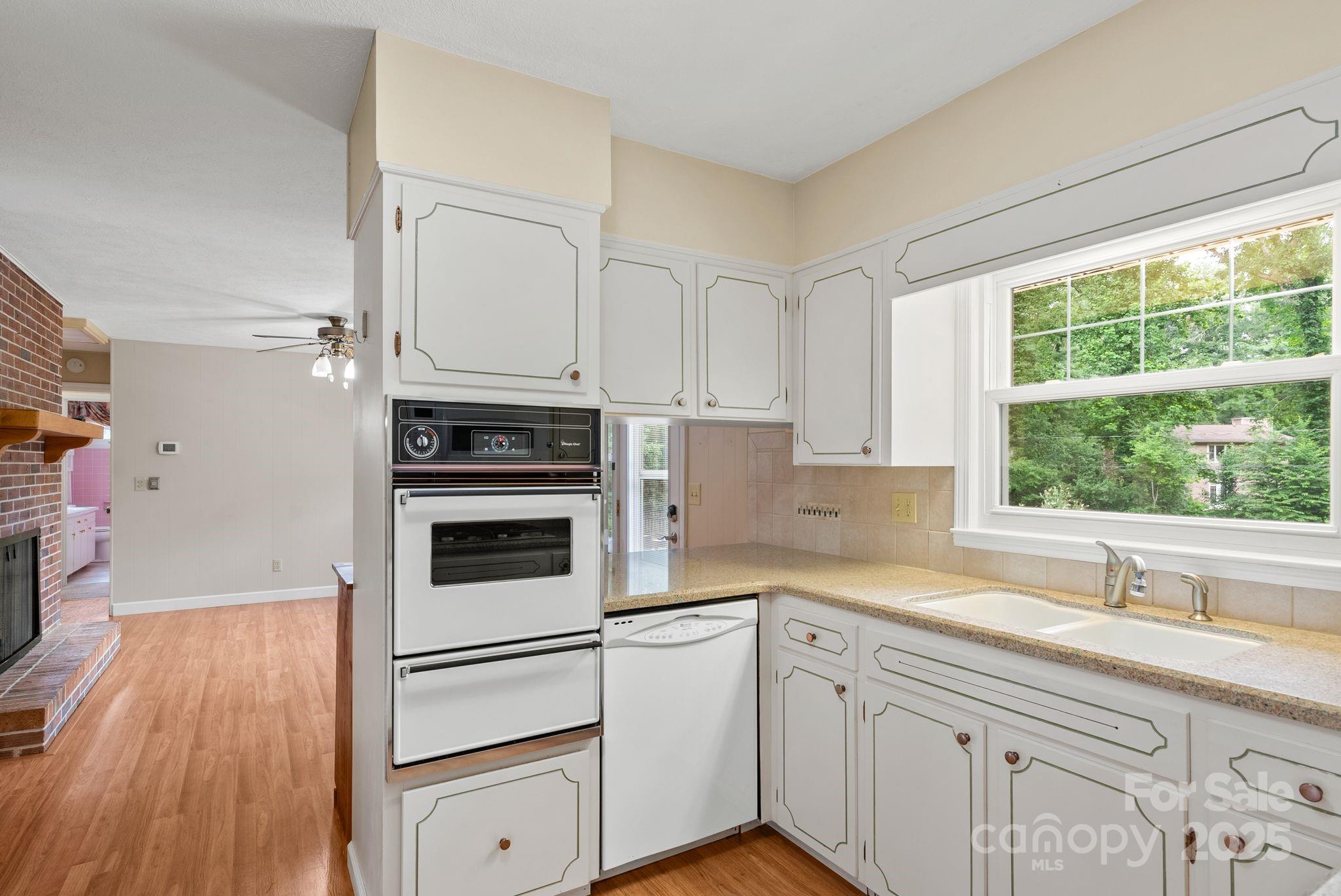6693 Brevard Road Etowah, NC 28729 - Photo 21 of 42 a kitchen with stainless steel appliances white cabinets and a wooden floor